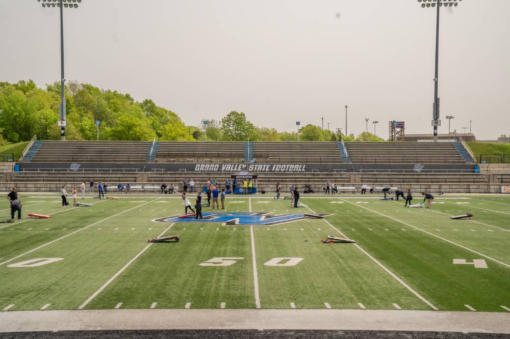 Aerial view of GVSU employees playing cornhole against one another on the football field in Lubbers Stadium